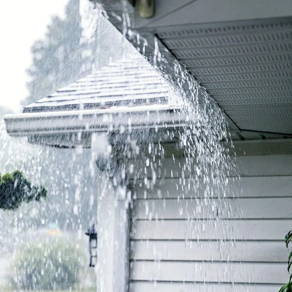 Rain gutter overflowing during a heavy rainstorm because of a clogged downspout