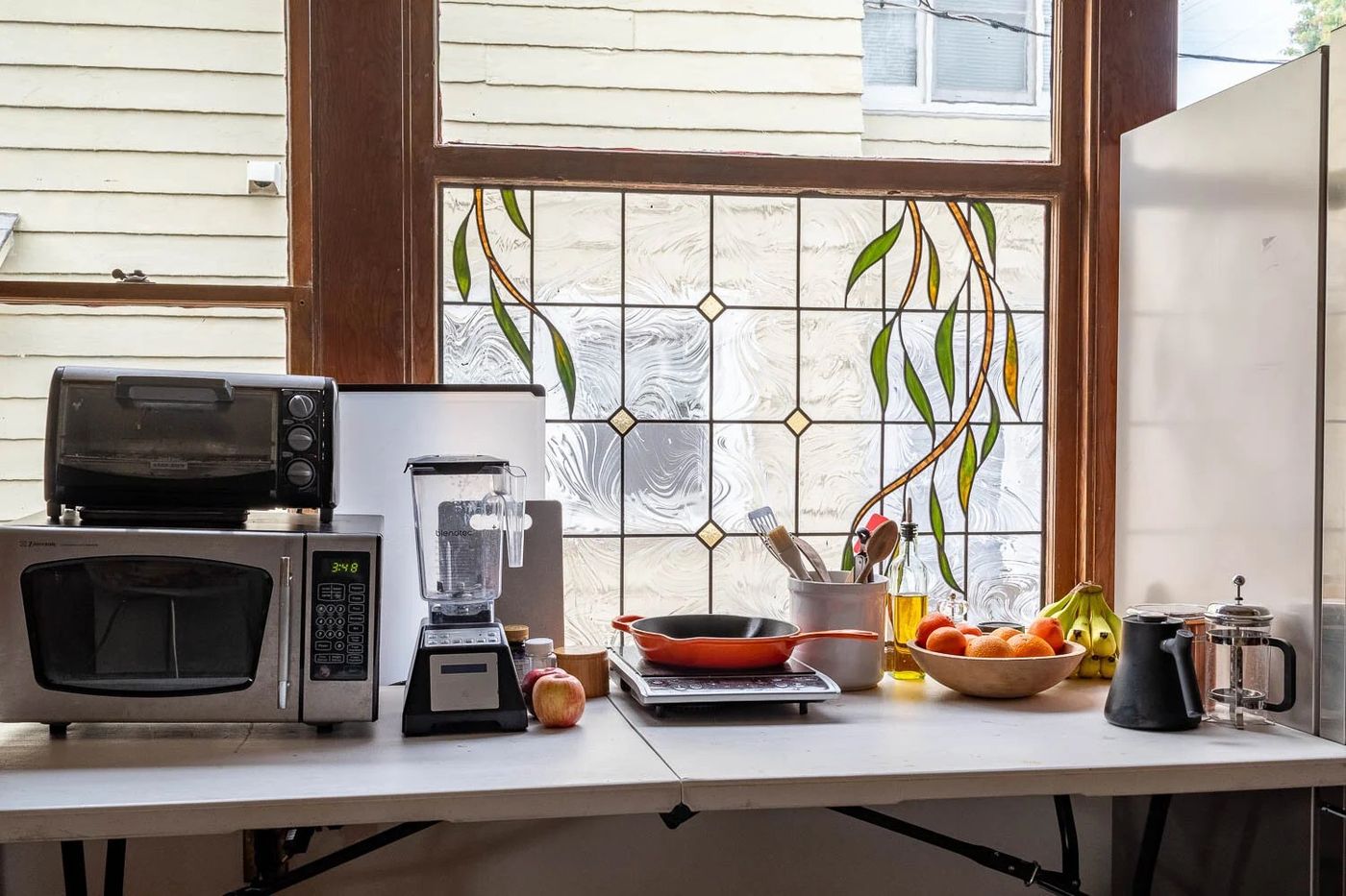 Temporary kitchen on a folding table with a microwave, toaster oven, blender, hot plate, and coffee maker