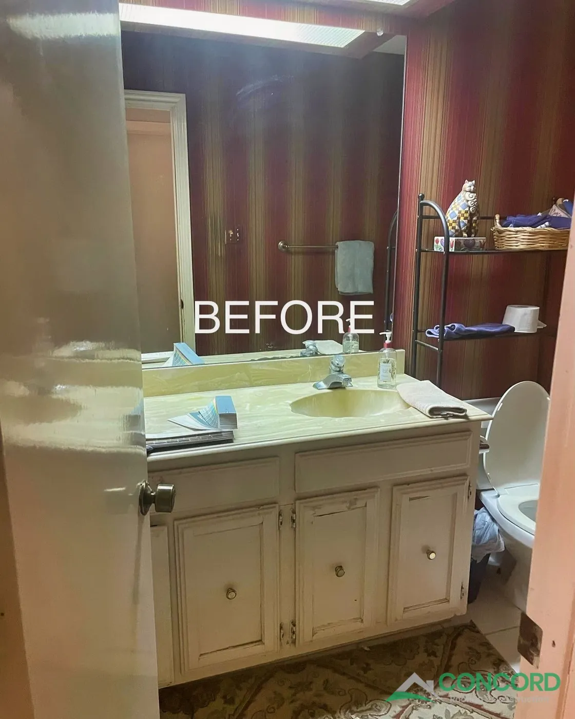 Dallas, TX hall bathroom before the remodel, with an older vanity and countertop, a large mirror, older flooring, and red striped walls