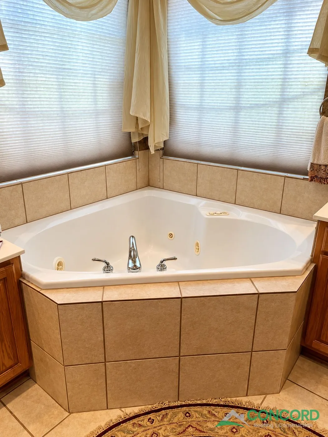 Master bathroom in Frisco, TX before the remodel, with a jetted corner tub in a tiled surround beneath two windows