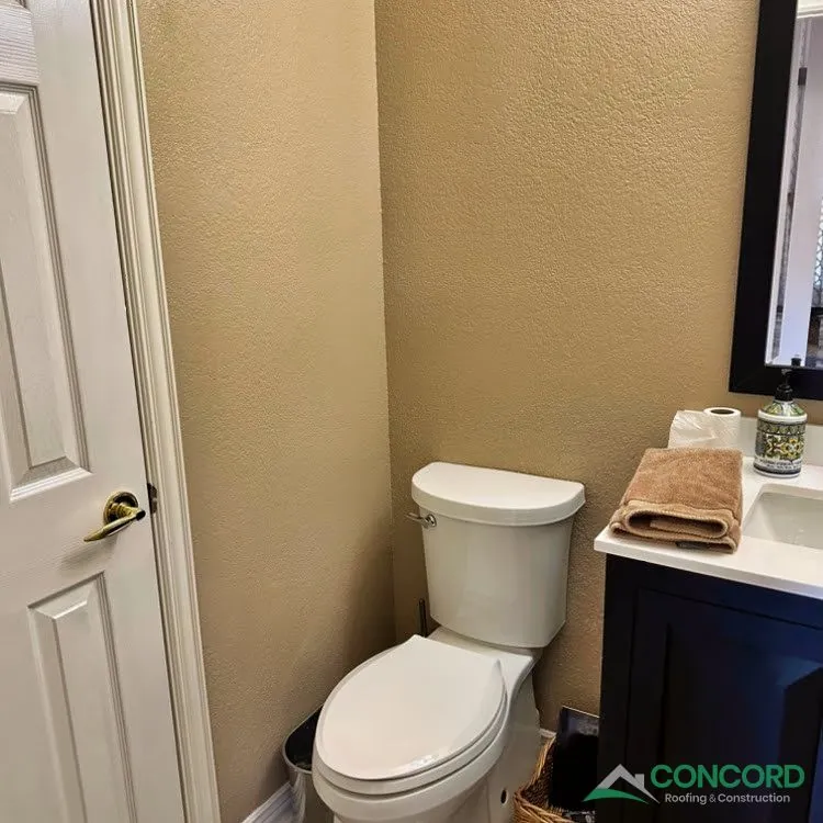New toilet and a dark blue vanity with a white countertop in a remodeled Frisco, TX powder bathroom