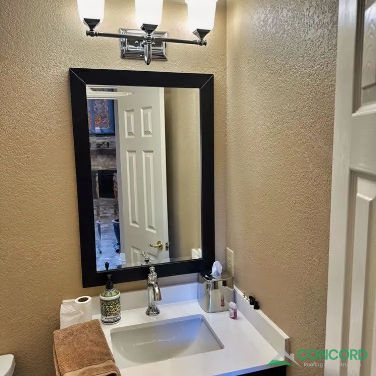 New powder bathroom vanity in Frisco, TX with a white countertop, undermount sink, black-framed mirror, and a three-light fixture