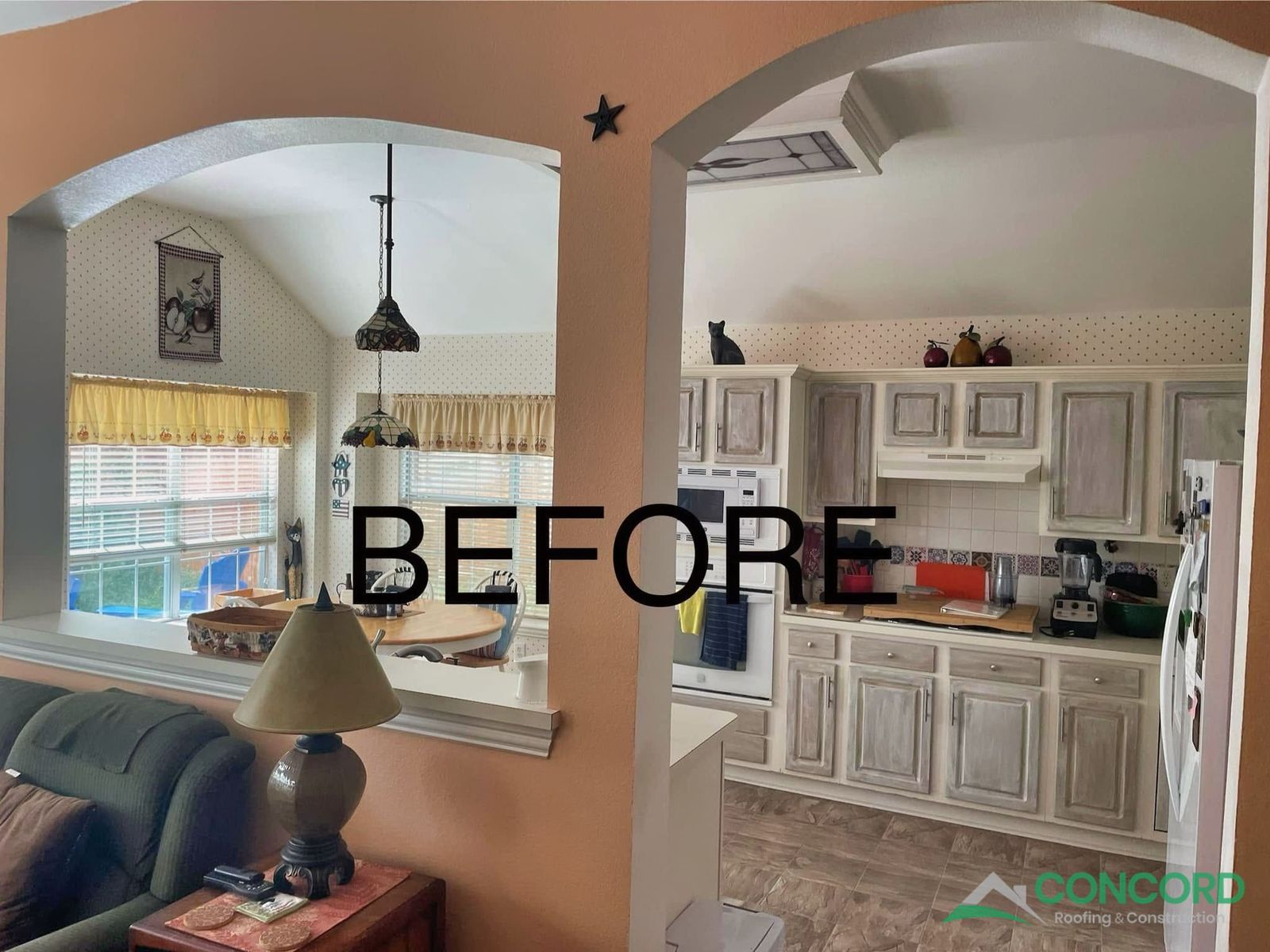 McKinney kitchen before the remodel, seen from the living room, with distressed cabinets, a wall oven tower, and patterned tile floor
