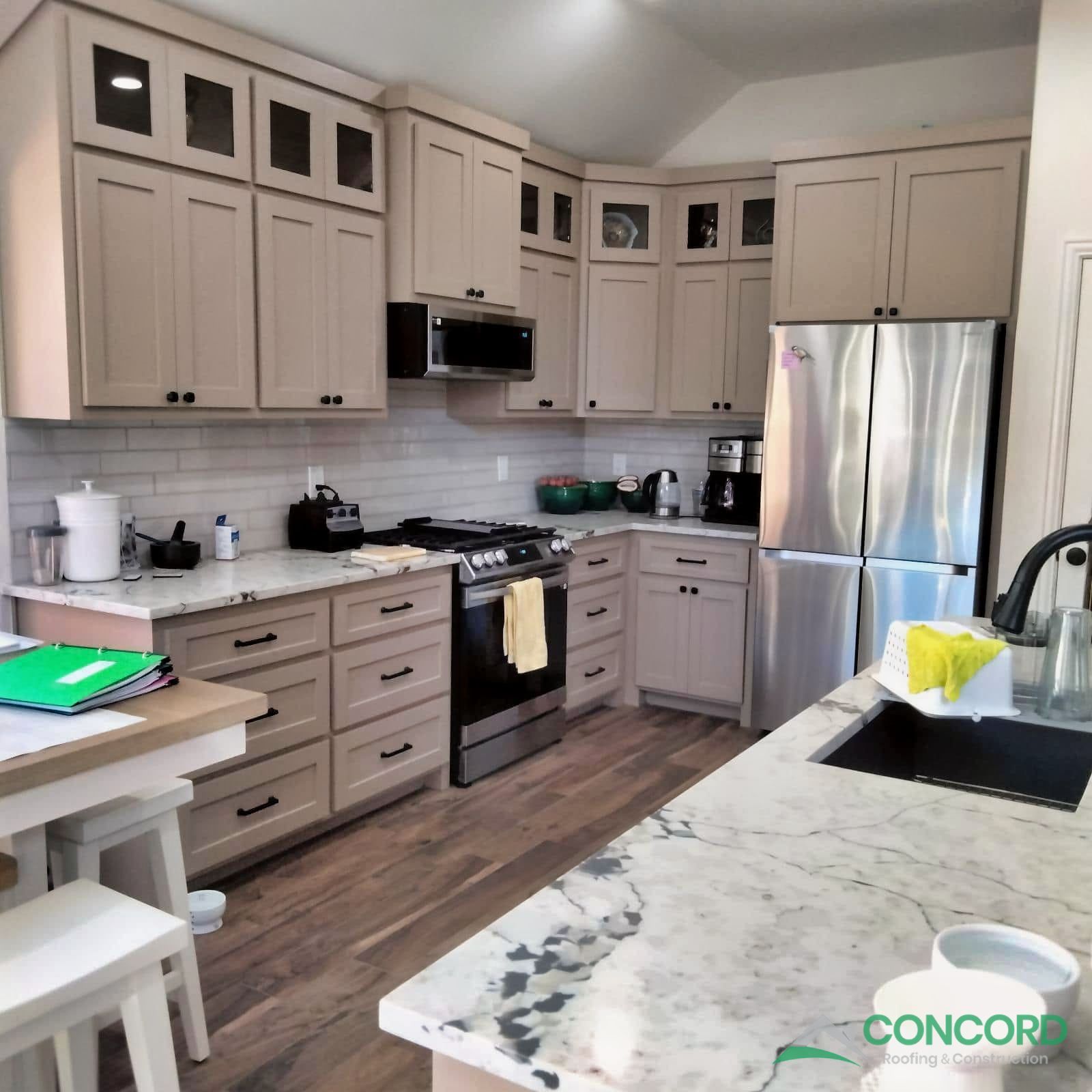 Finished McKinney kitchen with new stone countertops, a black undermount sink, painted cabinets, and wood-look flooring