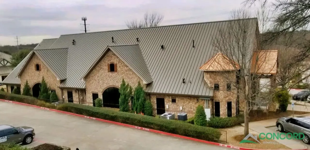 Finished standing seam metal roof with accent-color turret roofs on a stone pediatric clinic in McKinney, TX