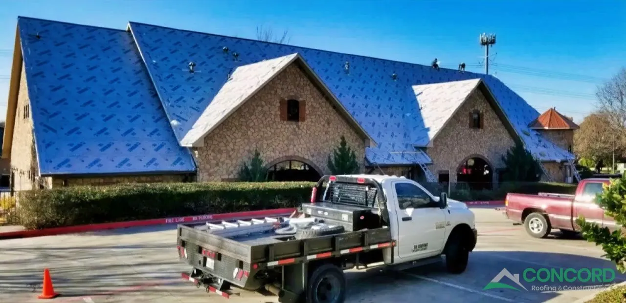 Underlayment going down across the roof of a McKinney, TX commercial building during a metal roof replacement