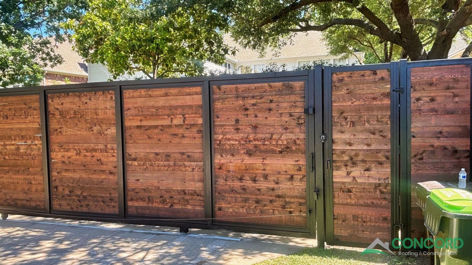 Sliding driveway gate and matching walk gate in a horizontal wood and steel fence