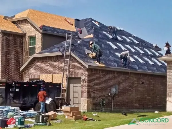 New felt underlayment on the roof of a brick home in Princeton, TX, with crews loading new shingles onto the roof