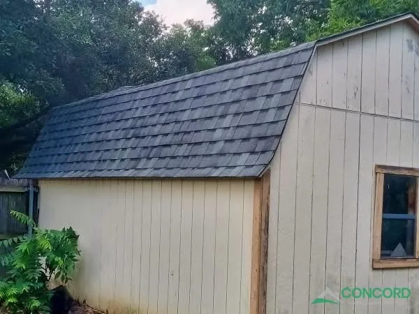 Small shed with a gambrel roof covered in new shingles in a backyard in Waxahachie, TX