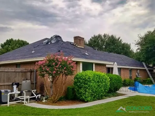 Crew removing the old storm-damaged roof from a single-story brick home in Waxahachie, TX, with a ladder against the eave